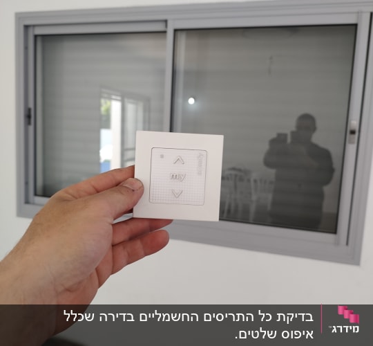 שלט רחוק מול חלון עם תריסים סגורים